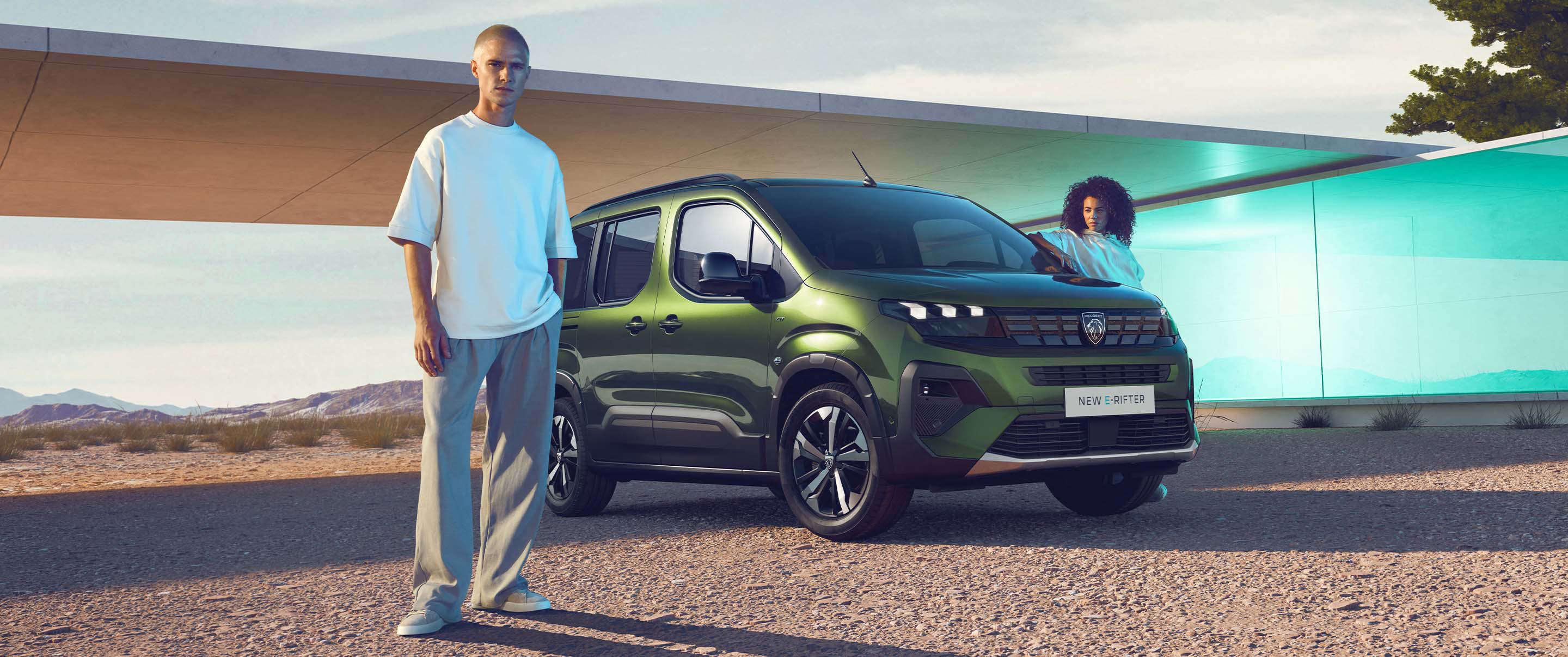 Чоловік стоїть перед Peugeot e-Rifter, жінка біля водійських дверей